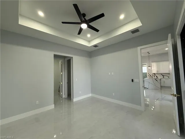 Spare room featuring recessed lighting, ceiling fan, a raised ceiling, and finished concrete flooring