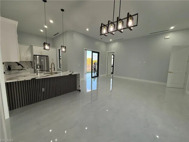 Kitchen featuring white cabinets, open floor plan, stainless steel fridge with ice dispenser, pendant lighting, and a peninsula