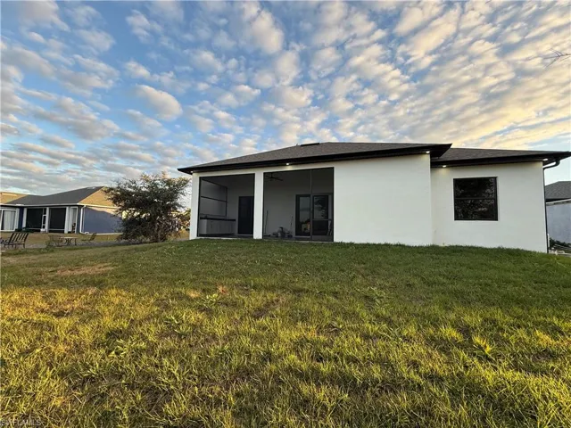 Back of property with a yard, stucco siding, a sunroom, and a ceiling fan