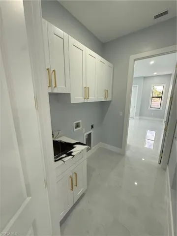 Laundry room featuring cabinet space, washer hookup, hookup for an electric dryer, light marble finish flooring, and recessed lighting