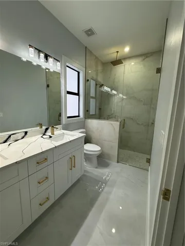 Bathroom with a marble finish shower, vanity, and marble finish flooring