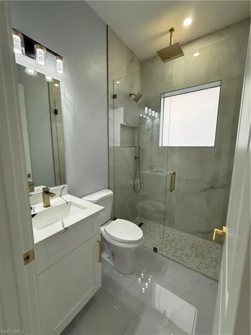 Bathroom with vanity and a marble finish shower