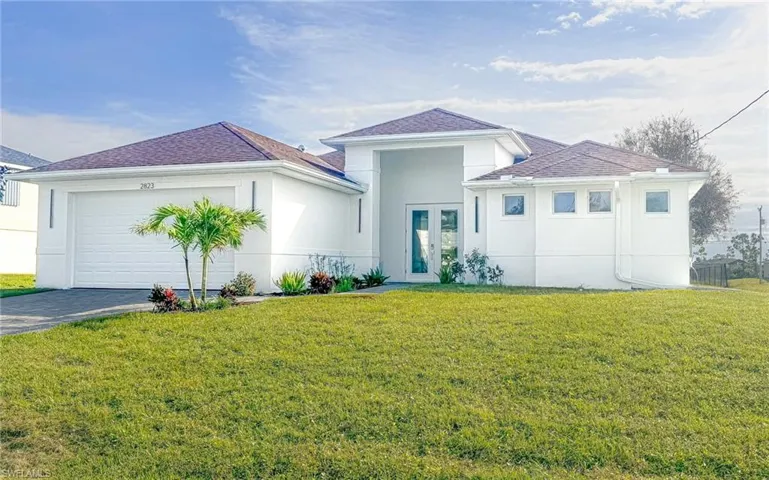 View of front of house with a front lawn, driveway decorative pavers and a 2 car garage