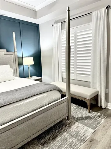 Bedroom with wood finished floors and crown molding