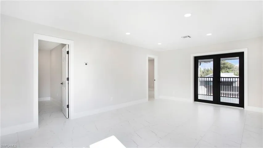 Empty room featuring recessed lighting, light marble finish flooring, and french doors