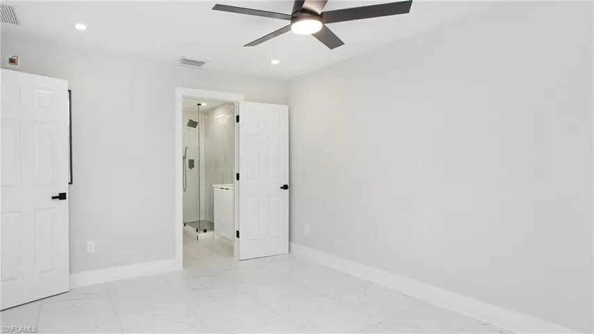 Unfurnished bedroom featuring light marble finish floors, a ceiling fan, recessed lighting, and ensuite bathroom