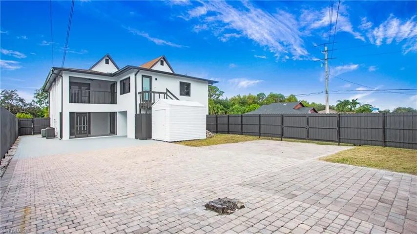 Rear view of house with a balcony, a fenced backyard, stucco siding, a patio, and driveway