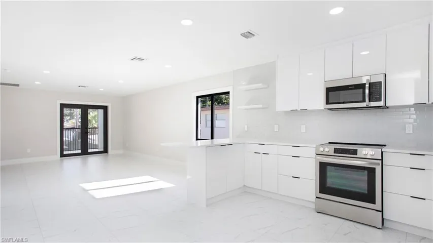 Kitchen featuring modern cabinets, open shelves, white cabinets, appliances with stainless steel finishes, and backsplash