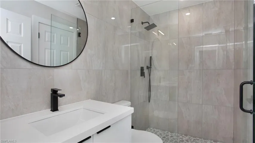 Bathroom featuring a stall shower, tile walls, and vanity
