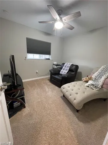 Carpeted living room with baseboards and a ceiling fan