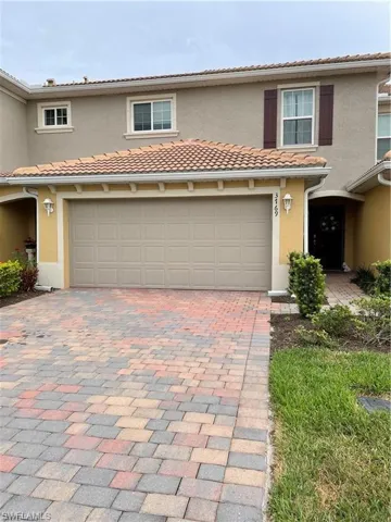 View of front of house with stucco siding, decorative driveway, a tile roof, and a garage