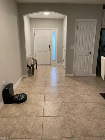 Foyer entrance featuring light tile patterned floors, arched walkways, and baseboards