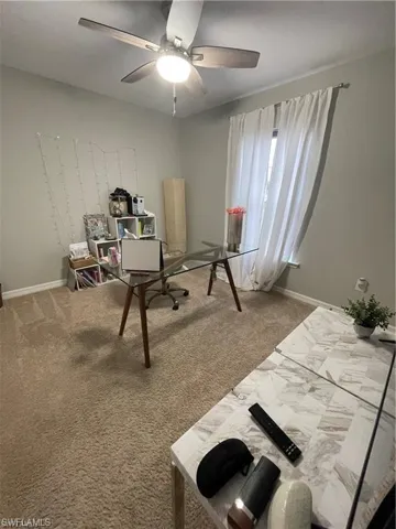Home office featuring ceiling fan, baseboards, and carpet floors