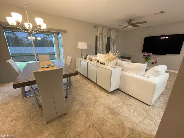 Living area featuring visible vents and ceiling fan with notable chandelier
