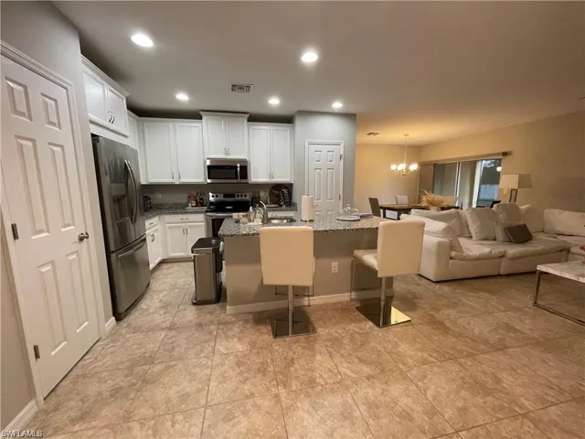 Kitchen featuring a chandelier, appliances with stainless steel finishes, white cabinetry, visible vents, and open floor plan