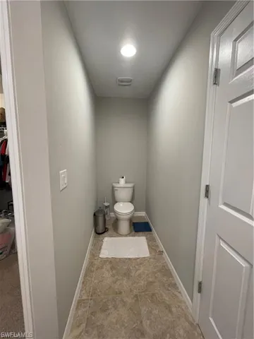 Bathroom with toilet, visible vents, and baseboards