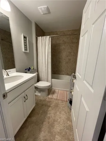 Bathroom featuring shower / bath combo, toilet, tile patterned flooring, and vanity