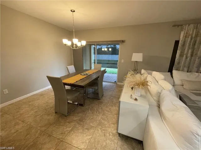 Dining area featuring light tile patterned floors, a chandelier, and baseboards
