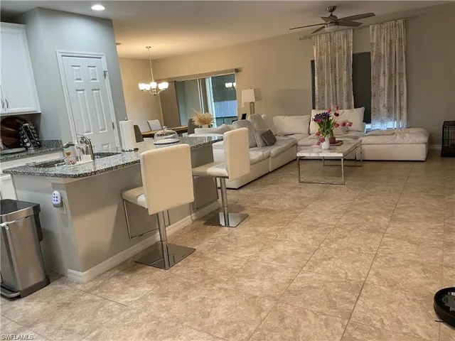 Living room with baseboards, recessed lighting, and ceiling fan with notable chandelier