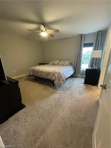 Bedroom featuring ceiling fan, baseboards, and carpet floors