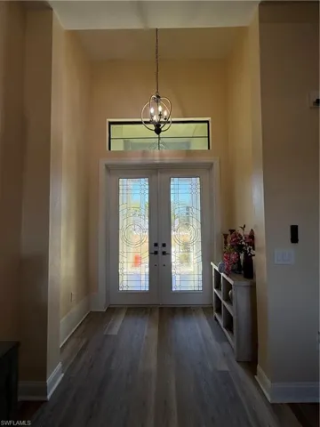 Foyer featuring french doors, dark wood-style floors, a chandelier, and a high ceiling