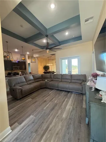 Living room featuring coffered ceiling, beamed ceiling, wood finished floors, recessed lighting, and french doors