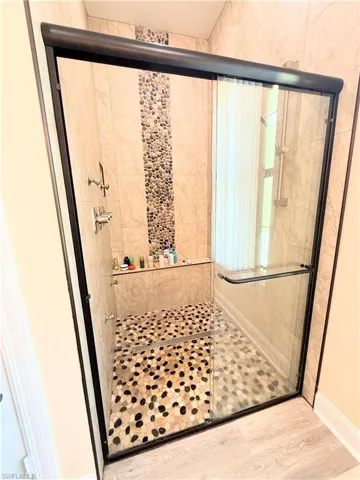 Bathroom with a shower stall and wood finished floors