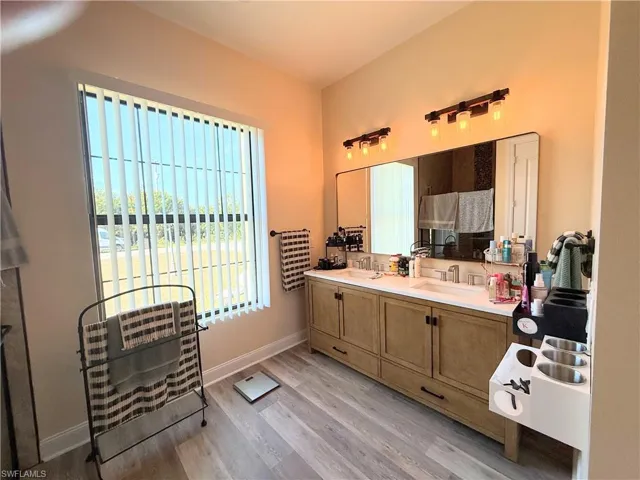 Full bathroom with healthy amount of natural light, double vanity, light wood finished floors, and a walk in shower