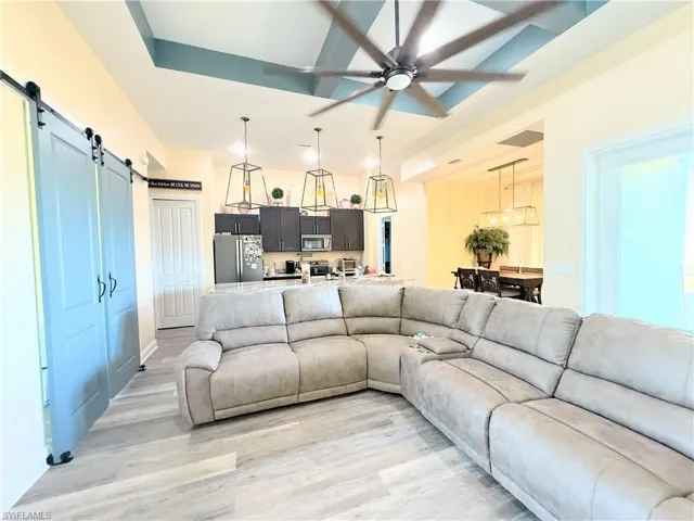 Living area featuring a barn door, light wood finished floors, and a ceiling fan