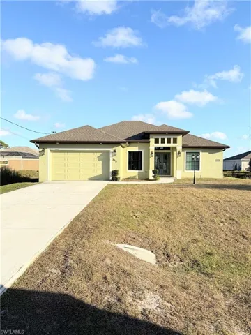 Prairie-style house with stucco siding, concrete driveway, an attached garage, and a front lawn