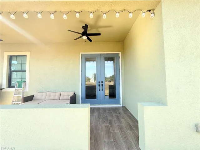 Entrance to property with ceiling fan, stucco siding, and french doors