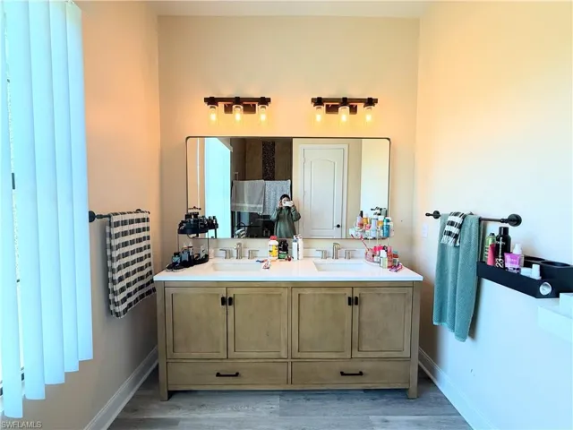 Full bath featuring double vanity and light wood finished floors