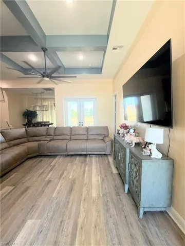 Living area featuring light wood finished floors, recessed lighting, a ceiling fan, and beamed ceiling