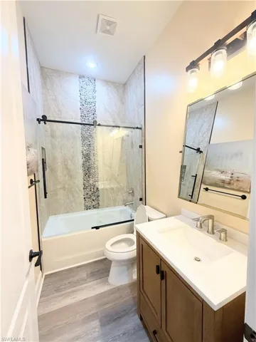 Full bathroom featuring vanity, shower / bath combination with glass door, and light wood finished floors