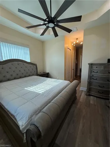 Bedroom featuring dark wood-style flooring, a closet, and ceiling fan