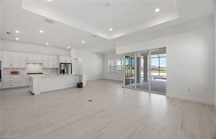 Unfurnished living room with a raised ceiling and ornamental molding