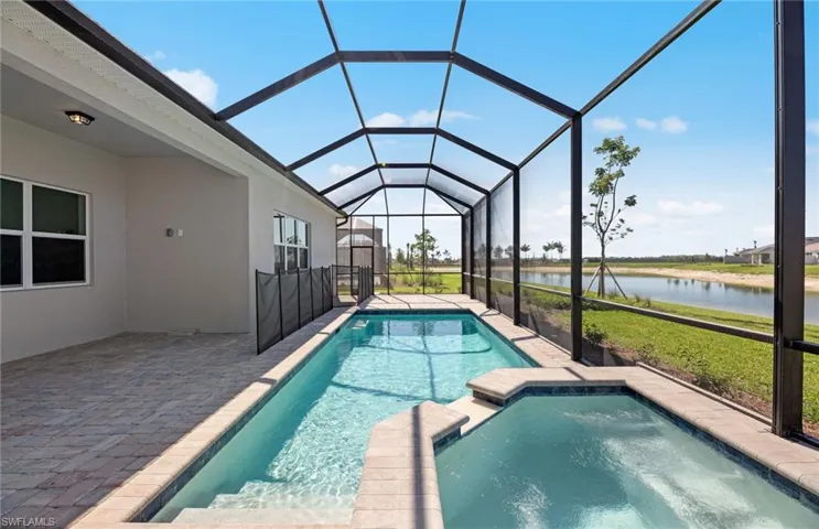 View of swimming pool featuring a patio, glass enclosure, and a water view