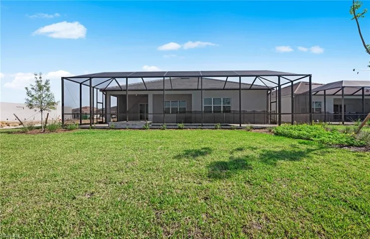 Rear view of property with glass enclosure and a lawn
