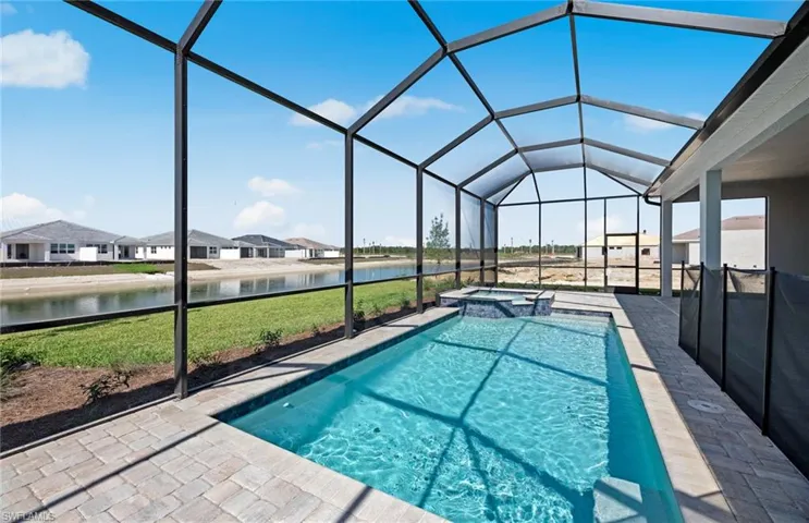 View of pool with an in ground hot tub, a lanai, a water view, and a yard
