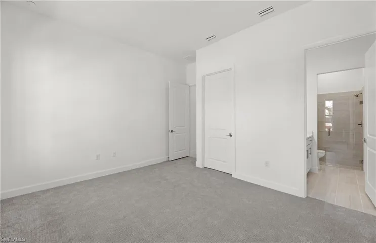 Unfurnished bedroom with light carpet and ensuite bathroom