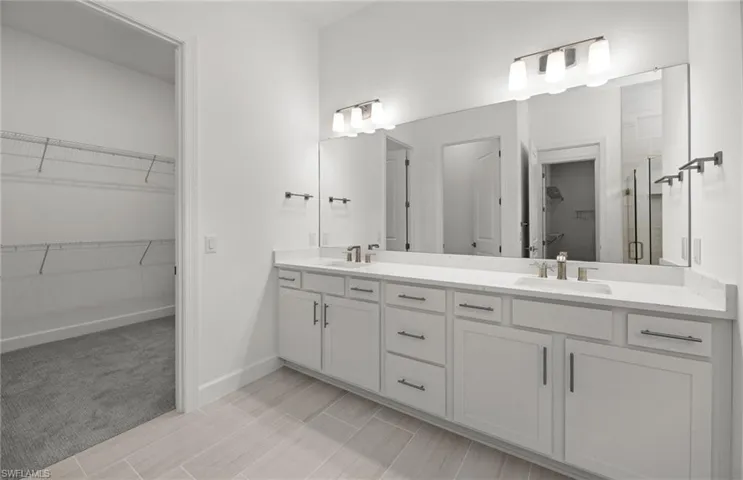 Bathroom with tile floors, dual sinks, and vanity with extensive cabinet space