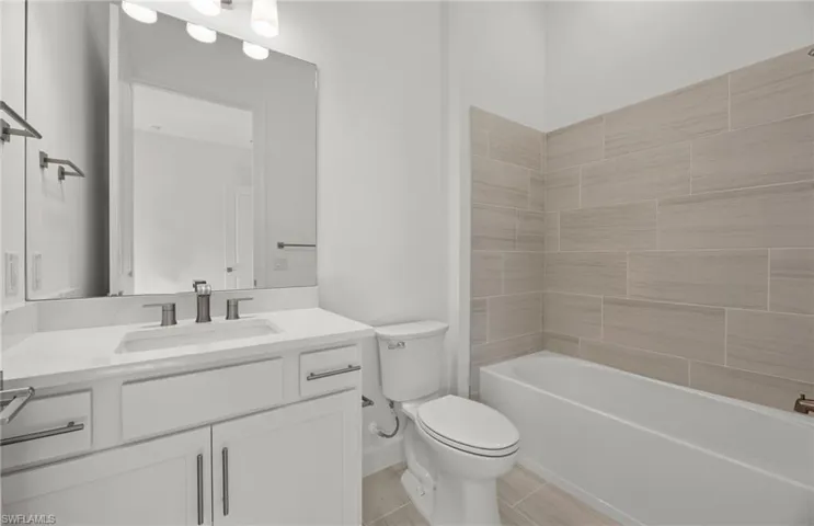 Full bathroom featuring tile flooring, oversized vanity, toilet, and tiled shower / bath combo