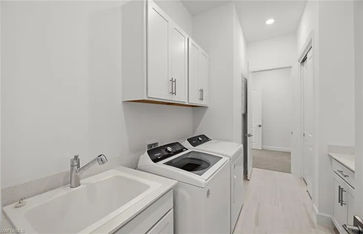 Laundry room with cabinets, washer and clothes dryer, washer hookup, sink, and light tile floors