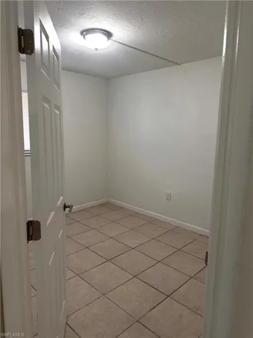 Unfurnished room featuring a textured ceiling and light tile patterned flooring