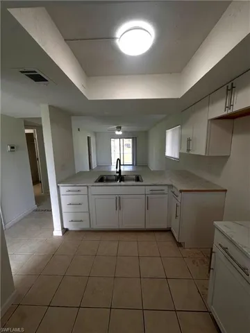 Kitchen with white cabinets, light tile patterned floors, and a raised ceiling