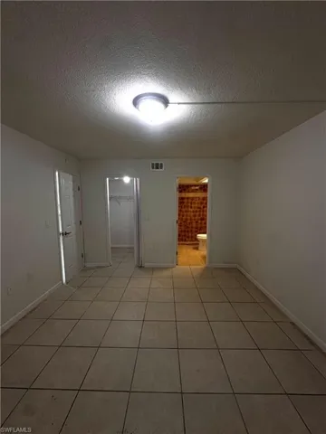 Empty room with a textured ceiling and light tile patterned floors