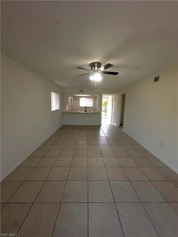 Empty room featuring light tile patterned floors, a ceiling fan, and healthy amount of natural light