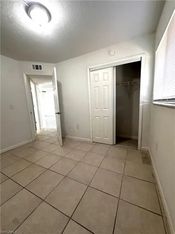 Unfurnished bedroom with a textured ceiling, light tile patterned floors, and a closet
