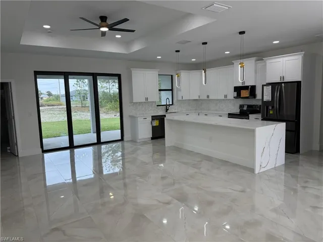 Kitchen featuring hanging light fixtures, white cabinets, black appliances, and a center island