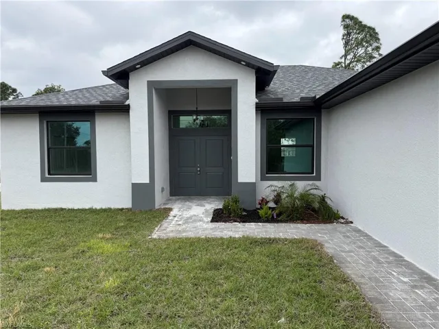 View of exterior entry featuring a lawn